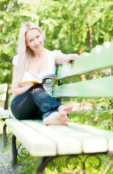 公園で本を読んでいる若い女性は — ストック写真