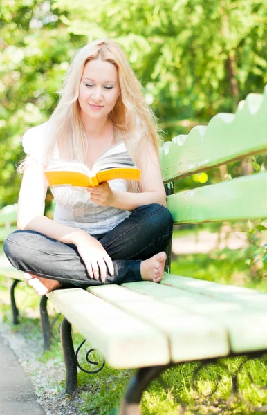 Jonge vrouw lezen boek in park — Stockfoto