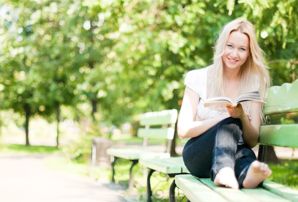 Jeune femme lecture livre dans le parc — Photo