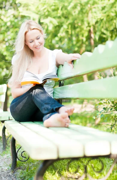Jonge vrouw lezen boek in park — Stockfoto