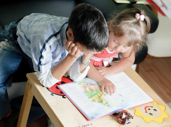 Un niño y su hermana están leyendo un libro. —  Fotos de Stock