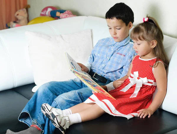 Мальчик читает книгу своей сестре — стоковое фото