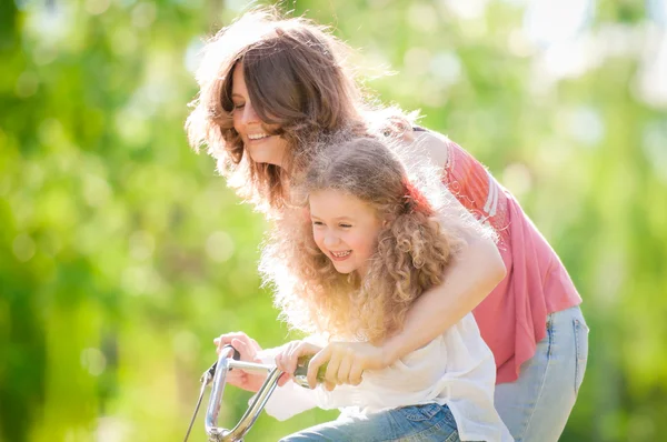 Joven madre y su hija en bicicleta Imágenes de stock libres de derechos