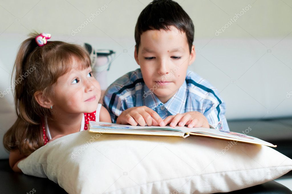 Boy reading a book to his sister