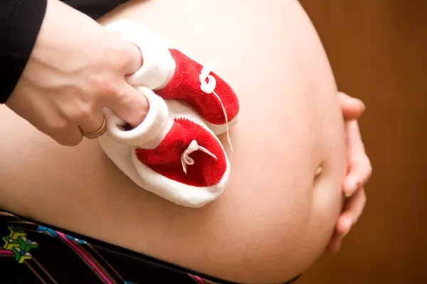 Mulher grávida, segurando botas de bebê — Fotografia de Stock
