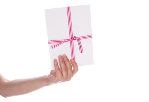 Envelop met een rood lint in haar hand geïsoleerd op wit — Stockfoto
