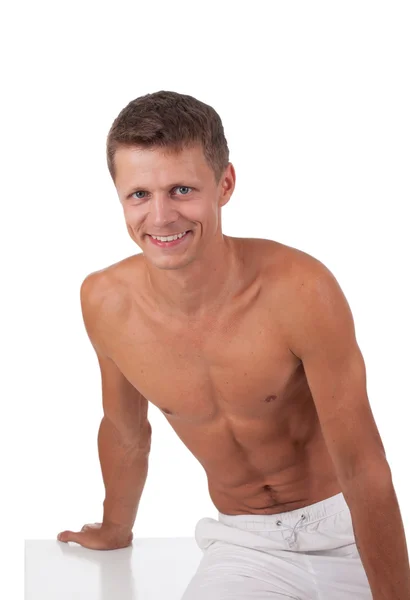 Muskulöser Mann sitzt isoliert auf weißem Grund — Stockfoto