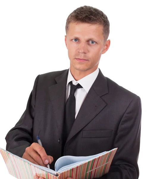 Businessman writes something in a book and looking at the camera — Stock Photo, Image