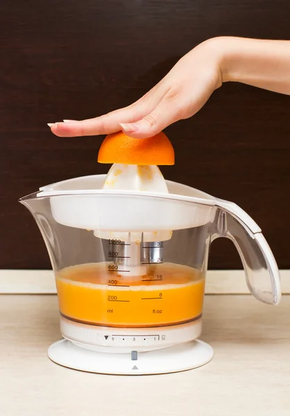 A woman squeezes orange juice in kitchen Stock Photo