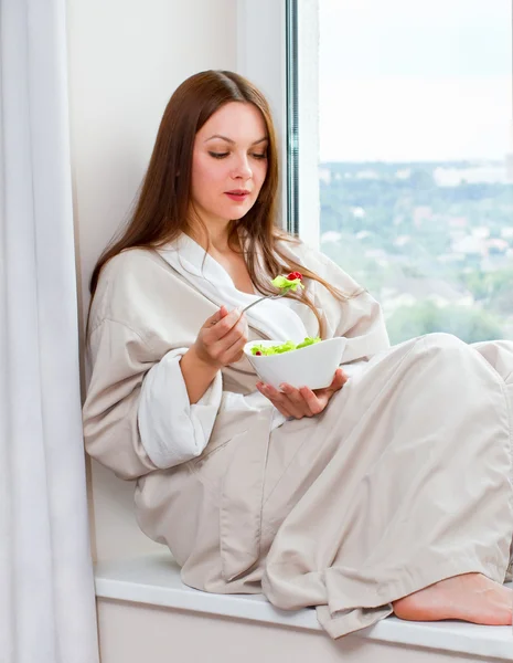Kvinne som spiser bringebærsalat stockbilde