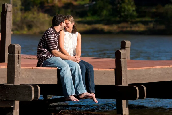 Mladý pár v lásce sedí naboso na doku — Stock fotografie