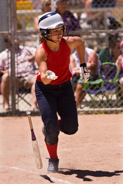 Feminino Softball jogador cai morcego e corre para a primeira base — Fotografia de Stock