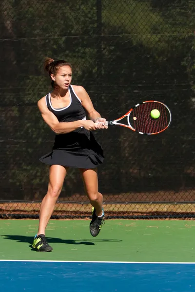Jugadora de tenis femenina golpea poderoso golpe de revés Imágenes de stock libres de derechos