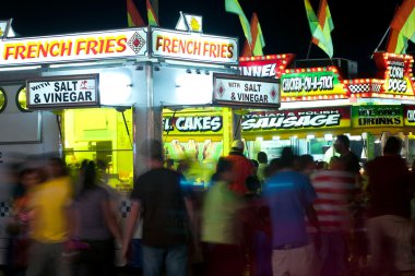 County Fair Patrons Move About Fast Food Vendors clipart