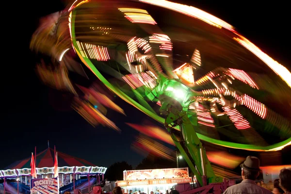 Světla a pohybu carnival Ride rozostření v noci — Stock fotografie