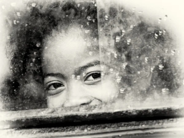 Little girl from Madagascar smiles behind the window