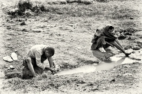Двое эфиопских мужчин чистят ноги в воде — стоковое фото