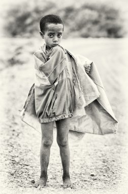 Etiyopyalı bir çocuk kameraya poz veriyor ve eski bir ceket giyer