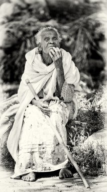 Etiyopya yaşlı bir kadın beyaz bir doku taşa oturur