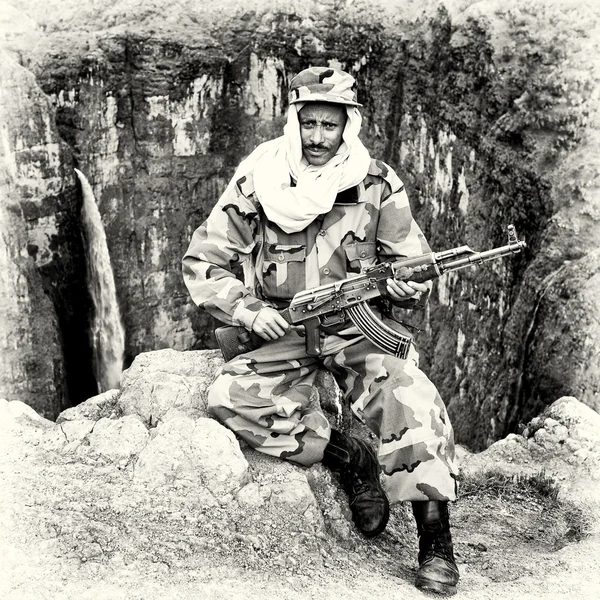 An Ethiopian man sits in the soldier clothes and with his gun — Stock Photo, Image