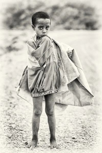Een Ethiopische jongen vormt voor de camera en draagt een oude jas — Stockfoto