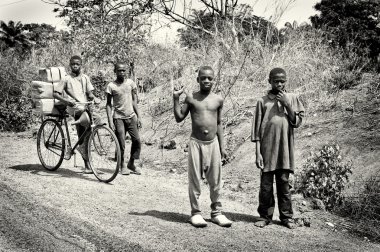 A group of Benin children walking in the field and riding a bicycle clipart