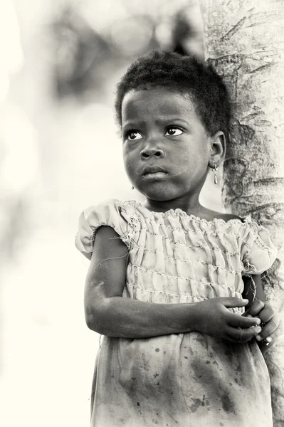 Een klein meisje houden verblijft in de buurt van de boom benin — Stockfoto