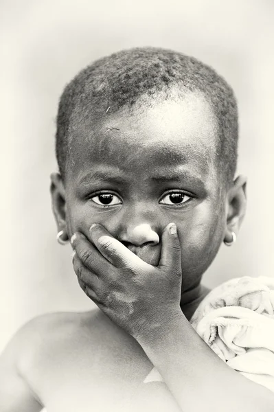 En benin lilla flickan stänger munnen med en hand — Stockfoto