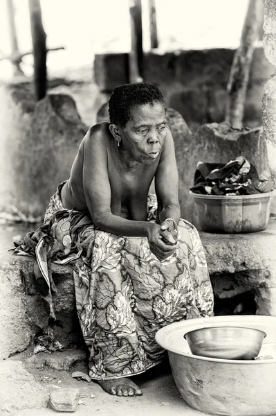 Старая дама из Бенина сидит и думает: — стоковое фото