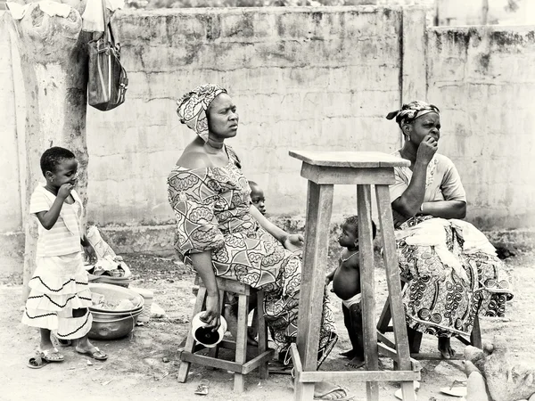 两个贝宁妇女和孩子们坐在靠近这把大椅子 — 图库照片