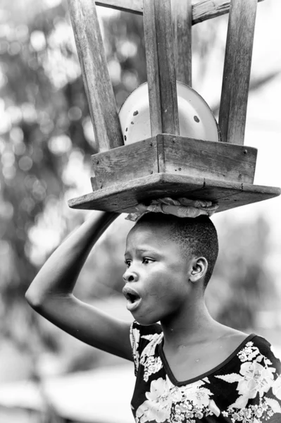 Benin vrouw draagt een houten stoel en plaat op haar hoofd — Stockfoto