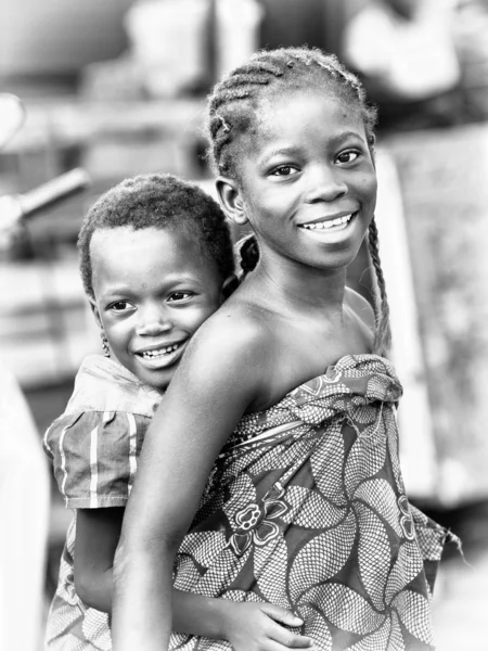 Две маленькие девочки Бенина обнимают друг друга и улыбаются — стоковое фото