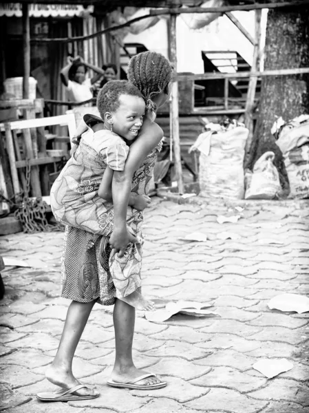 La pequeña Benin lleva a su hermana pequeña en su espalda —  Fotos de Stock