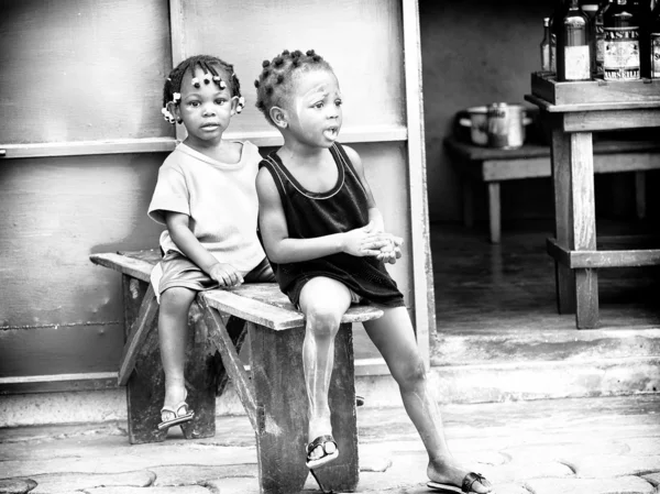 Two little Benin girls sit together on a bench — Stock Photo, Image