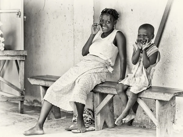Benin chlapce s jeho matkou sedět na lavičce — Stock fotografie