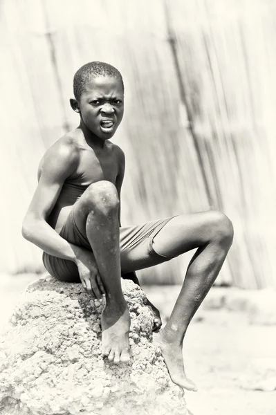 Jeune Bénin garçon assis sur la pierre — Photo