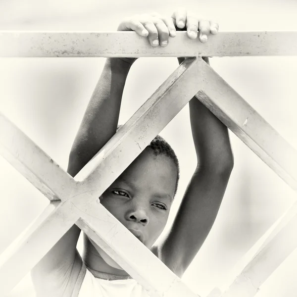 Young Benon boy hangs on the wooden construction — Stock Photo, Image
