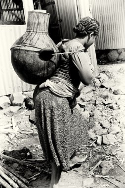 An Ethiopian woman with a jar of water on her back clipart