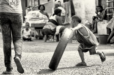 Gana'lı çocuk çalışır ve bir lastik ile oynuyor