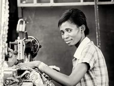 Gana'lı bir kadın dikiş makinesini kullanarak diker