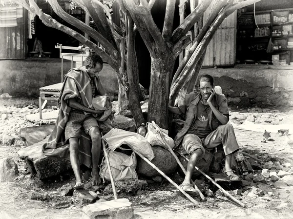 Two Ethiopian men with wooden sticks sit on the stone — Stock Photo, Image