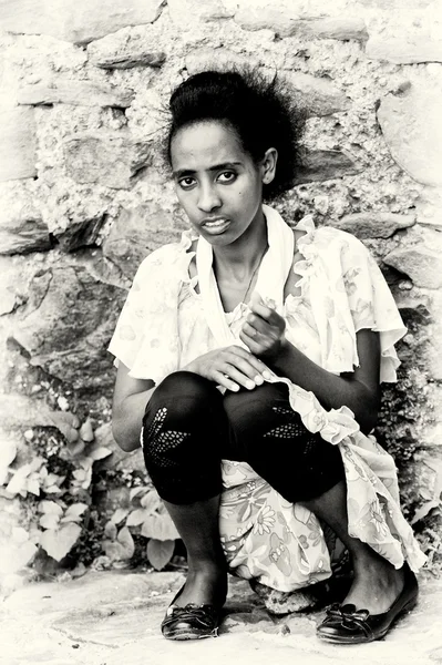 Jeune femme éthiopienne assise près d'un mur de pierre — Photo