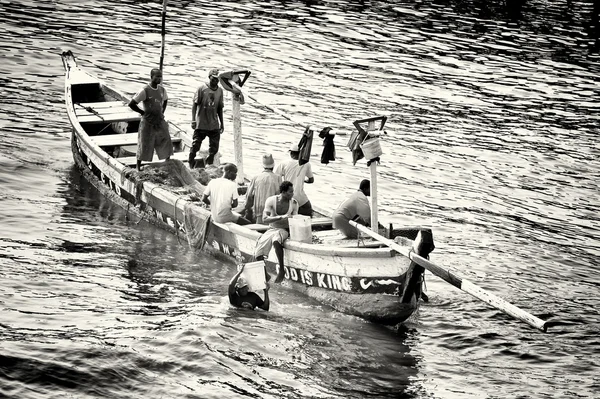 Un gruppo di marines ghanesi fa remare la barca con i pesci e uno di loro trasporta a riva dei backet con i pesci — Foto Stock