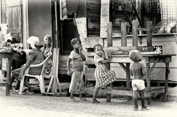 Dos mujeres ghanesas y algunos niños parecen algo con lo que jugar. — Foto de Stock