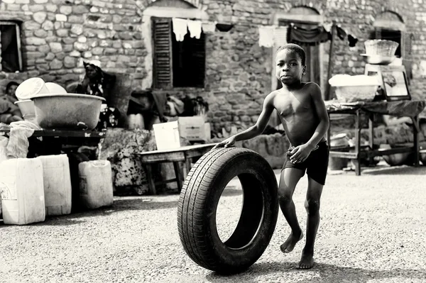 Pequeño chico ghanés juega con un neumático —  Fotos de Stock