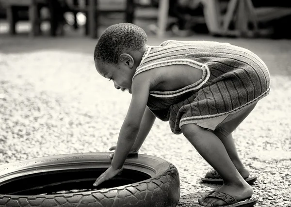 Маленький ганский мальчик играет с шиной — стоковое фото