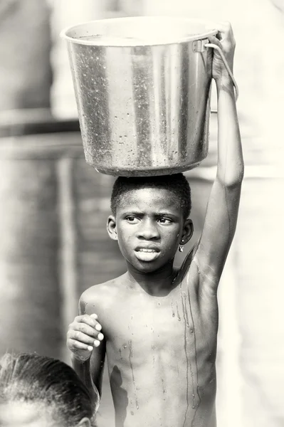 El joven ghanés lleva una cuenca de agua sobre su cabeza. — Foto de Stock