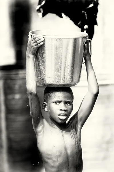 Молодой ганский мальчик с бассейном воды — стоковое фото