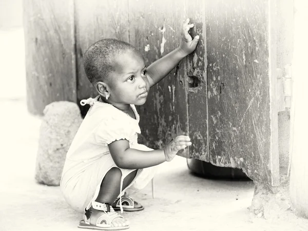 Ghański dziewczynka siedzi blisko ściany — Zdjęcie stockowe