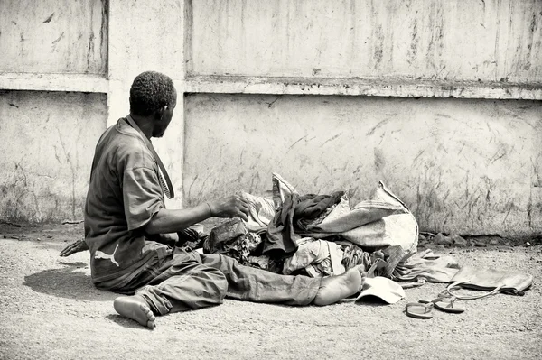 Un Ghanéen s'assoit par terre avec ses affaires. — Photo